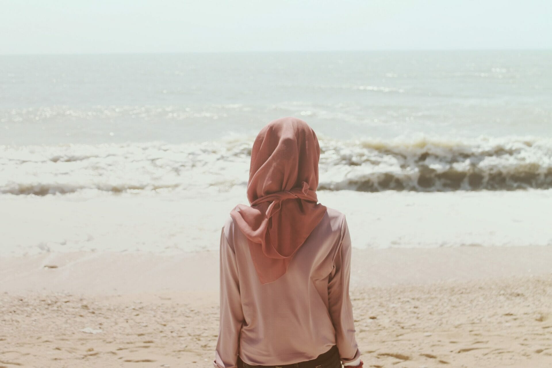 Woman looking out at the sea from the beach on a sunny day