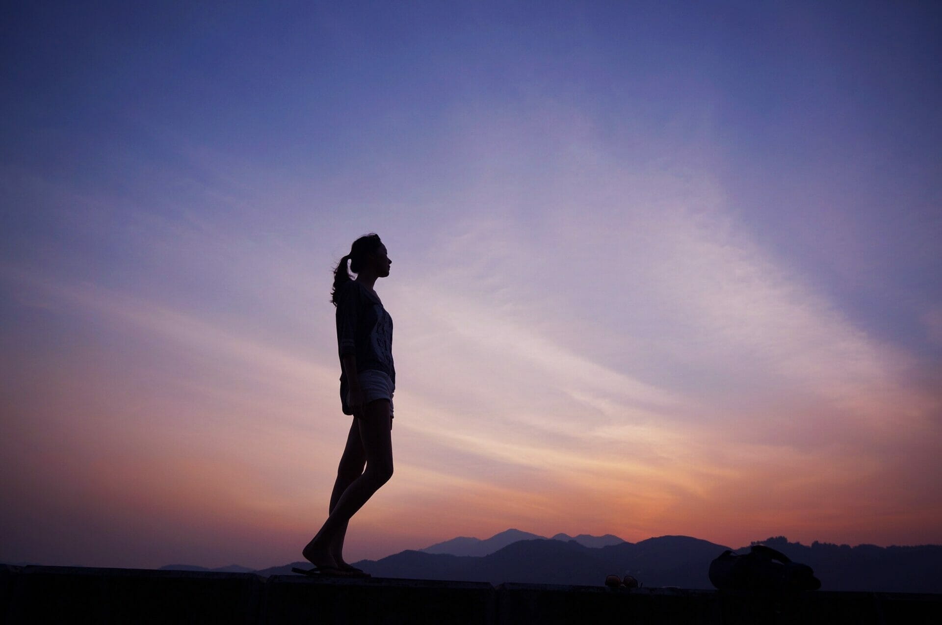 silhouette of woman standing against the sky at dusk