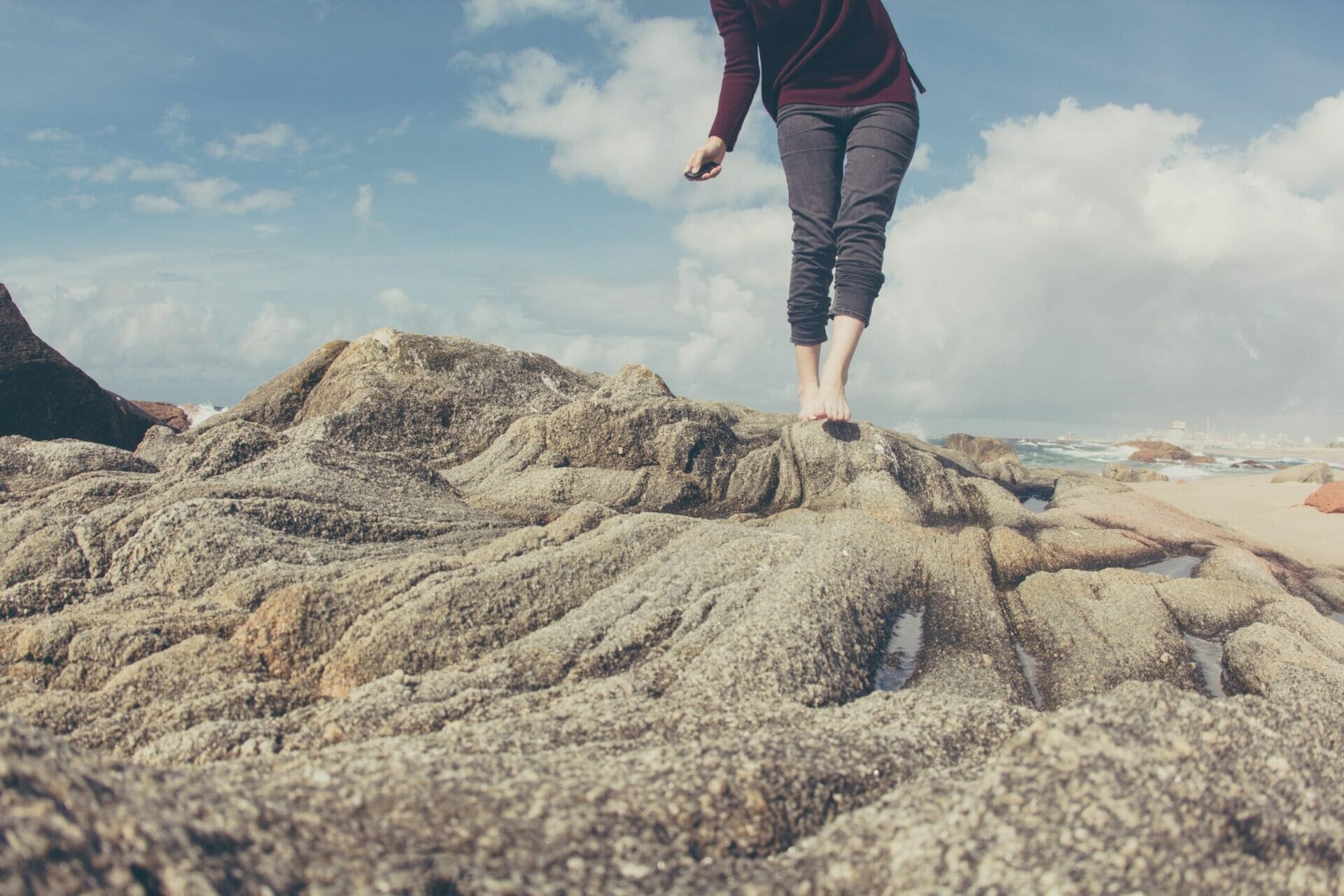 woman's feet walking across rocks on the beach